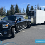 Black pickup truck towing a large mobile refrigerated trailer with external cooling unit in a parking lot