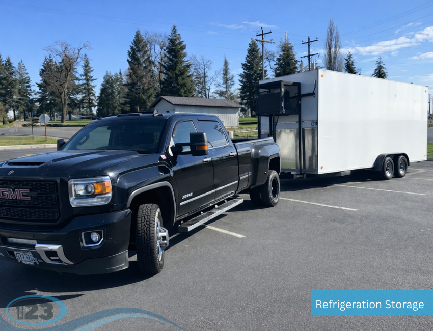 Black pickup truck towing a large mobile refrigerated trailer with external cooling unit in a parking lot