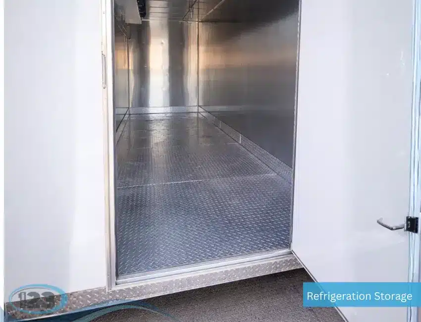 Open door view into an empty refrigerated trailer with metal walls and diamond plate flooring.