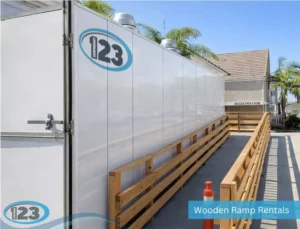 Wooden accessibility ramp with sturdy handrails providing safe wheelchair access to a temporary modular facility.